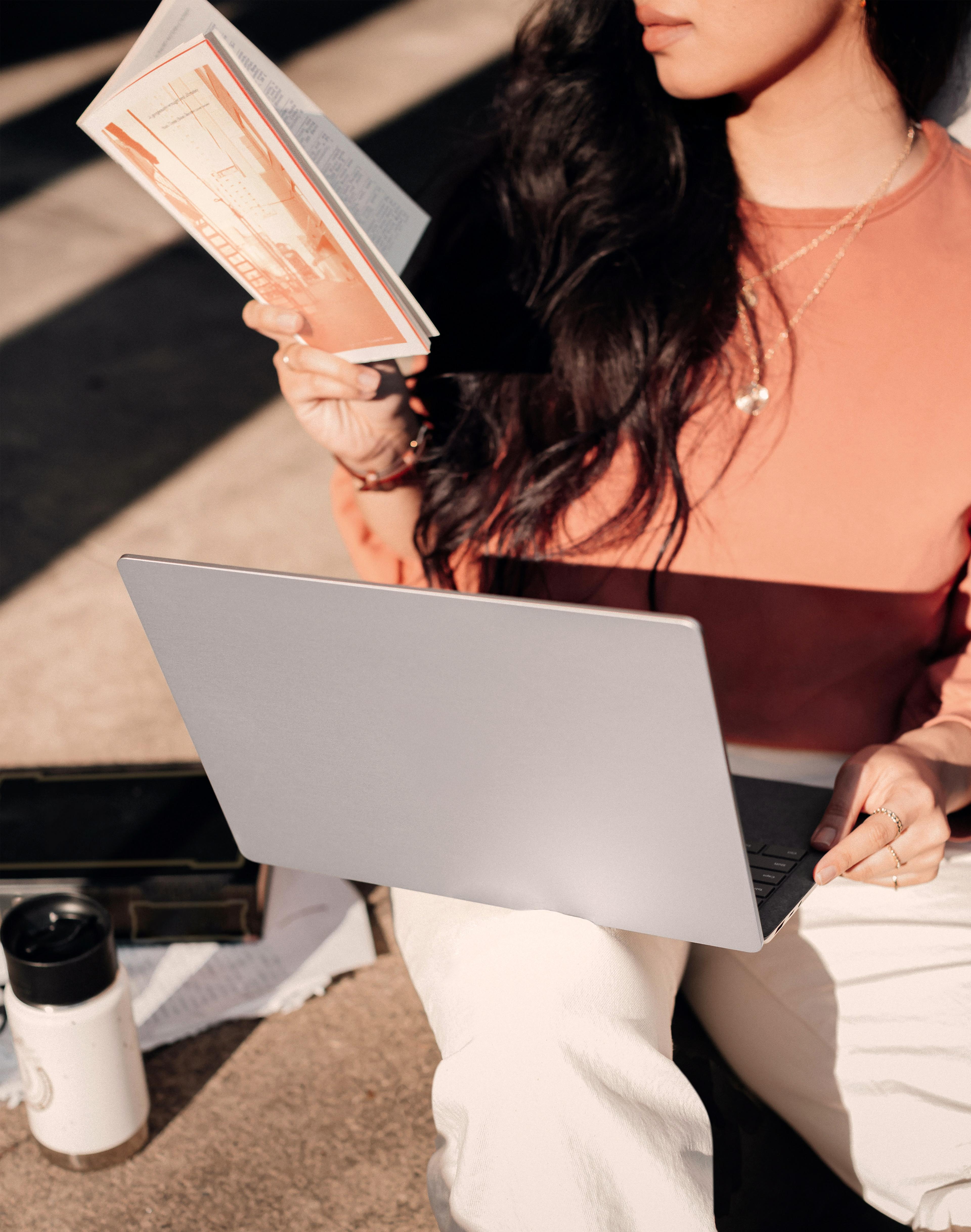 Guest working on a laptop outdoors with a book at MODE by YHA