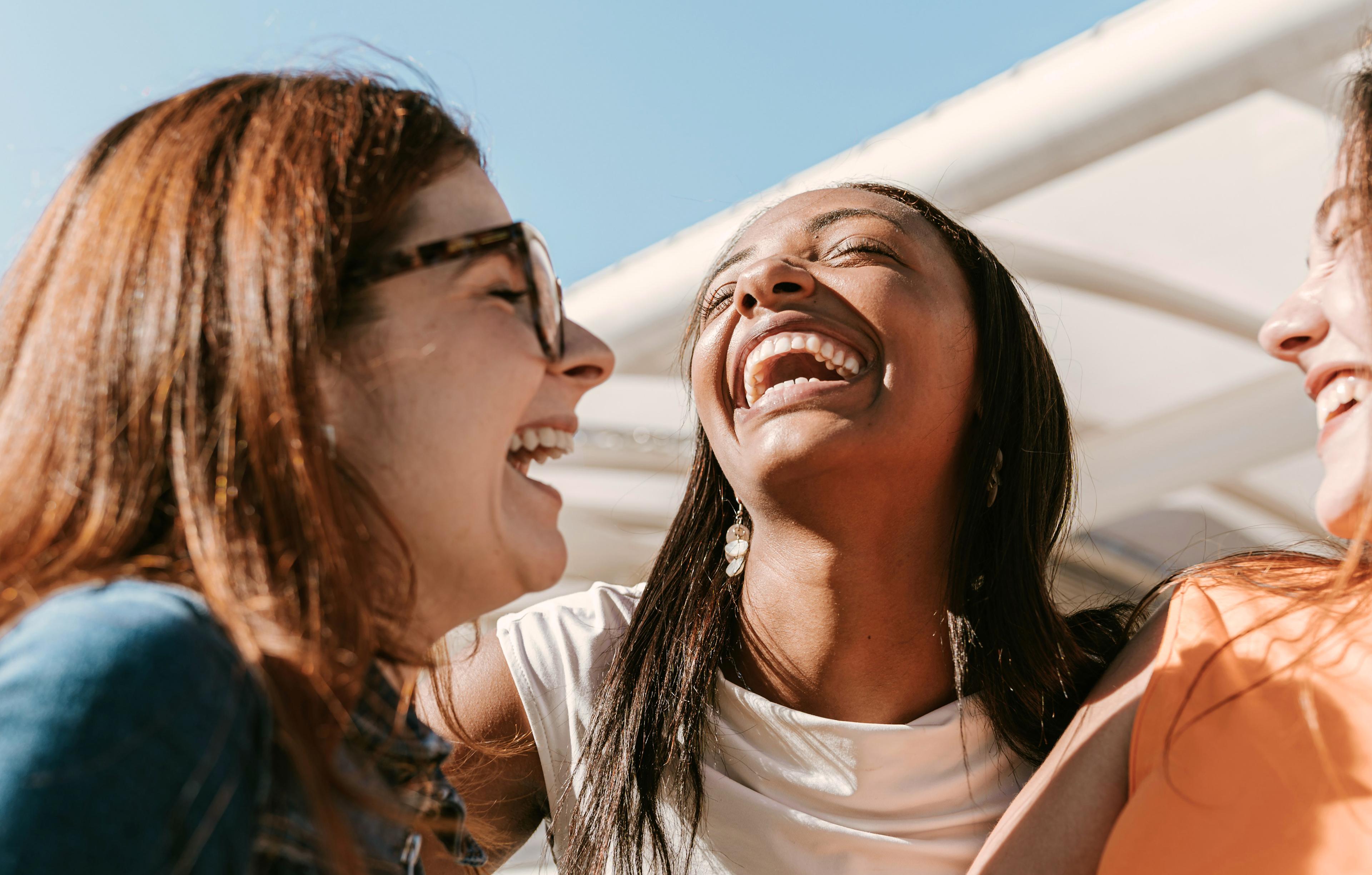 Three friends laughing together outdoors at MODE by YHA Sydney
